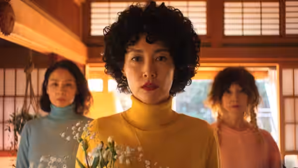 Haru (Rinko Kikuchi) in yellow turtleneck holding flowers with two women