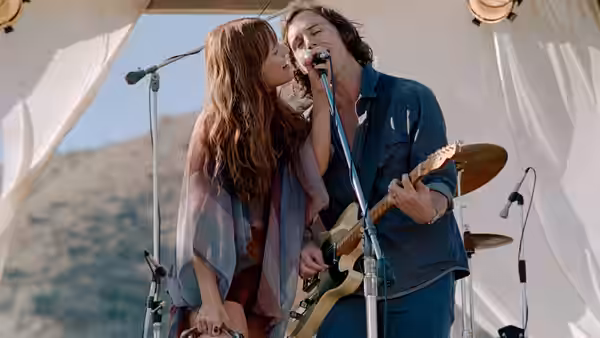 Daisy Jones kisses Billy Dunne on the cheek during a performance