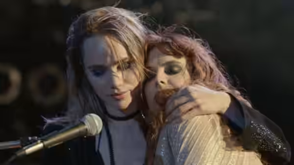 Daisy Jones and Karen Sirko embrace at the microphone