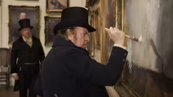 JMW Turner (Timothy Spall) paints on a large canvas as a gentleman watches in a gallery