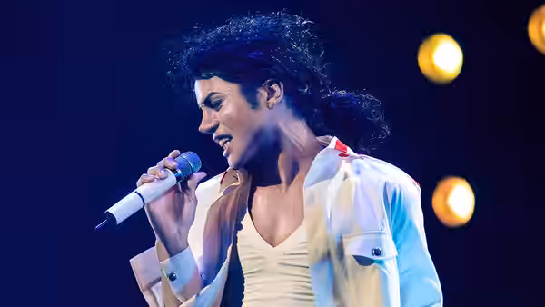 Michael (Jaafar Jackson) singing into a microphone under stage lights