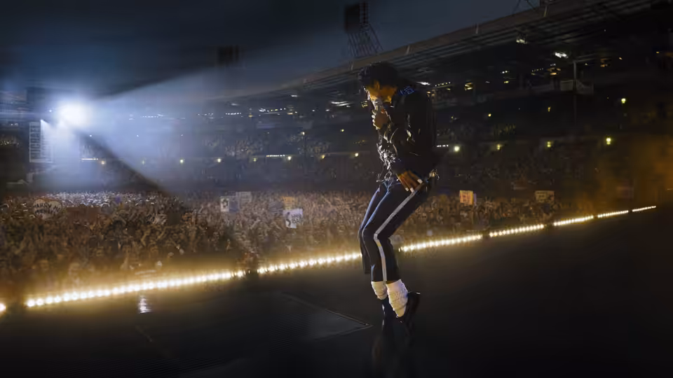 Michael (Jaafar Jackson) dancing on stage before a packed stadium crowd