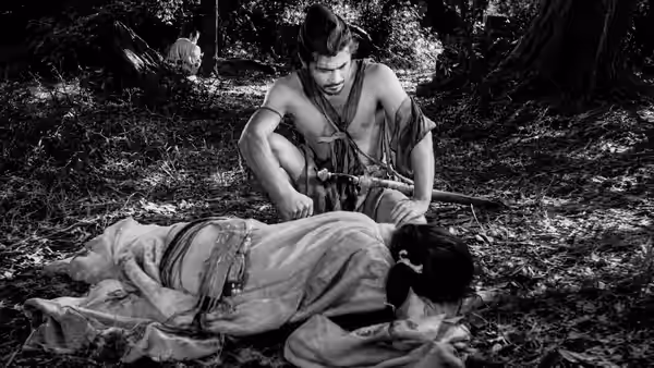 Tajômaru (Toshirō Mifune) crouching over Masako (Machiko Kyō) on the forest floor