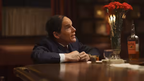 Richard Rodgers (Andrew Scott) seated at a bar with red carnations nearby