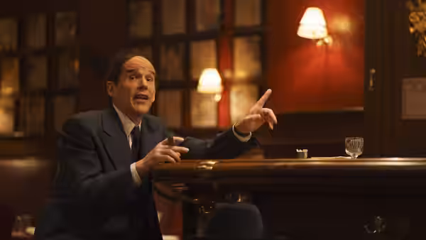 Richard Rodgers (Andrew Scott) gesturing while speaking at a wooden bar