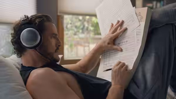 Alex Serian (Pedro Pascal) reading sheet music while wearing headphones