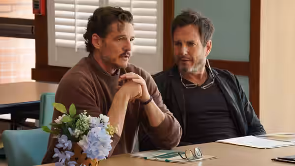 Alex Serian (Pedro Pascal) sits beside a man at a table, listening