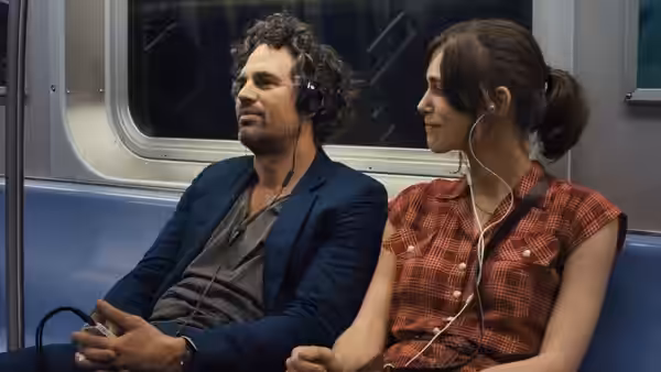 Dan (Mark Ruffalo) and Gretta (Keira Knightley) listening with earphones on a subway train
