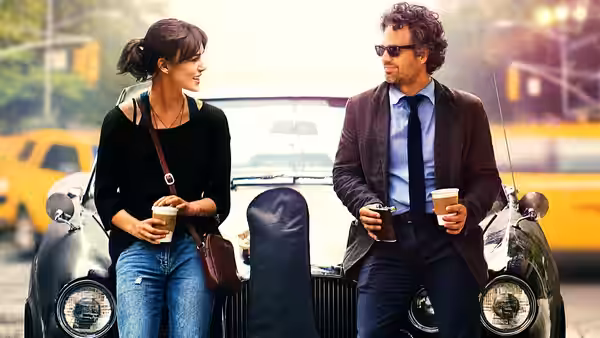 Dan (Mark Ruffalo) and Gretta (Keira Knightley) holding coffee beside a vintage car