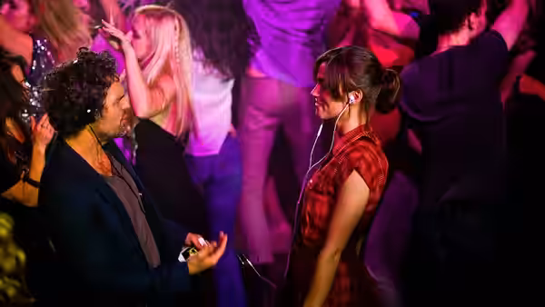 Dan (Mark Ruffalo) and Gretta (Keira Knightley) with earphones at a crowded nightclub