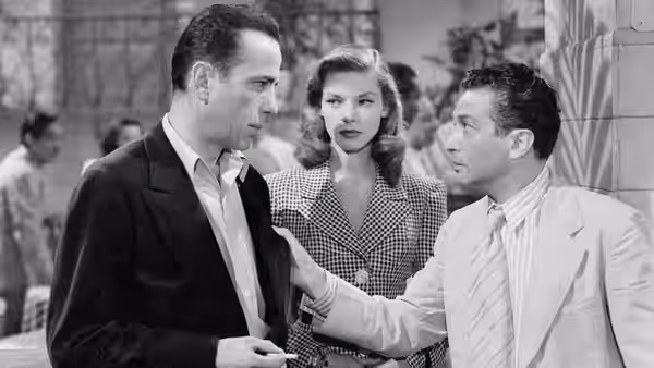 Harry Morgan (Humphrey Bogart) listens as a man gestures beside Marie Browning (Lauren Bacall)