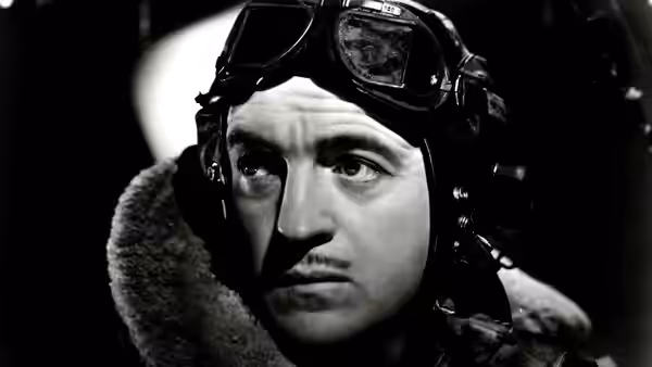 Peter Carter (David Niven) in flying helmet and goggles looking upwards