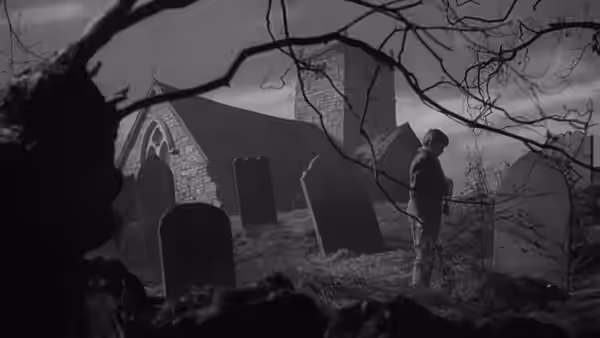 Young Pip (Anthony Wager) standing among gravestones outside a stone church