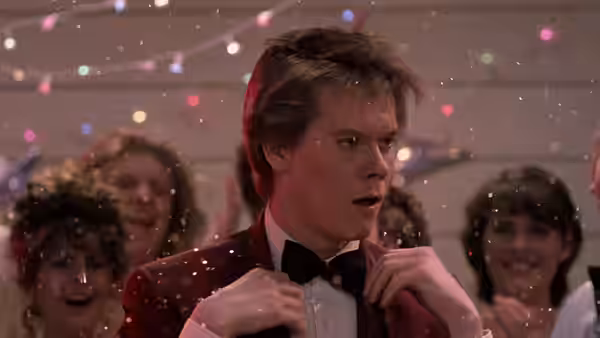 Ren (Kevin Bacon) adjusting his bow tie amid falling confetti at the dance