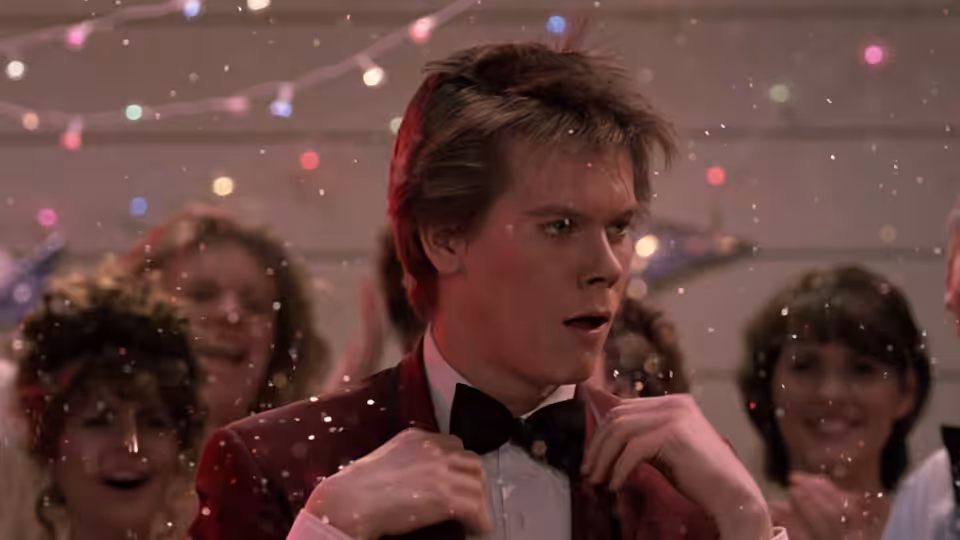 Ren (Kevin Bacon) adjusting his bow tie amid falling confetti at the dance