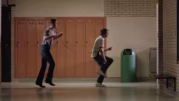 Ren (Kevin Bacon) holding a tape player while Willard dances in the school hallway