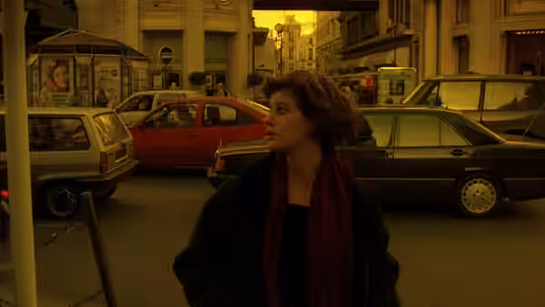 Véronique in red scarf standing on busy city street at dusk