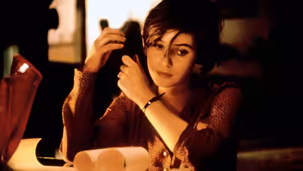 Véronique holding telephone receiver to her ear in office