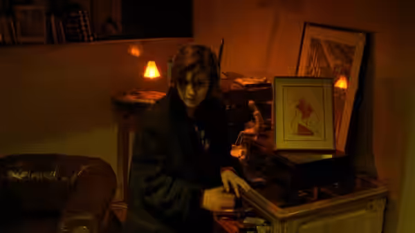 Woman with headphones adjusting record player in dimly lit room