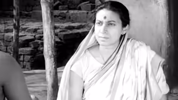 Woman in sari sits against wall and looks to one side