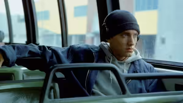Jimmy (Eminem) wearing headphones while riding on a bus