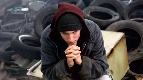 Jimmy (Eminem) sitting among tires with hands clasped