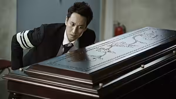 Go Gun-su (Lee Sun-kyun) peers at an ornate coffin