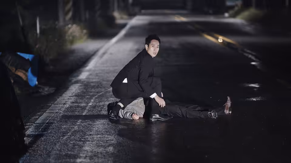 Go Gun-su (Lee Sun-kyun) kneels over a body on a wet road