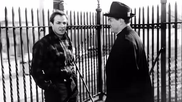 Terry Malloy (Marlon Brando) talking to Father Barry (Karl Malden) by a fence