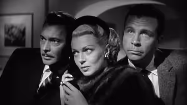 Georgia Lorrison (Lana Turner) stands between two men, holding a cigarette