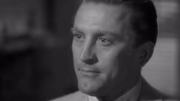 A clean-cut man in a suit gazes off to the side