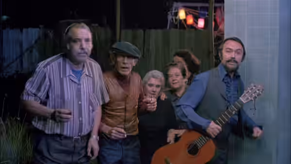 Five people gathered outside a building at night one holding a guitar