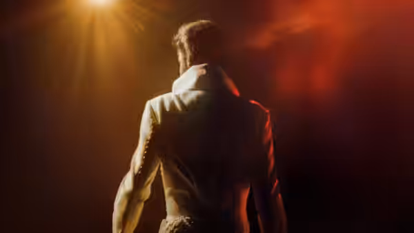 Elvis Presley standing on stage viewed from behind under bright spotlights