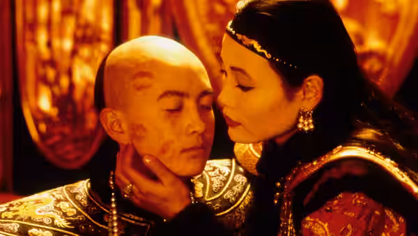 Pu Yi (John Lone) sits with eyes closed as Wan Jung (Joan Chen) touches his face