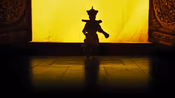 Silhouetted child in traditional robe and hat walks toward a glowing yellow doorway