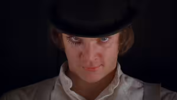 Alex (Malcolm McDowell) in close-up wearing a bowler hat and long false eyelashes