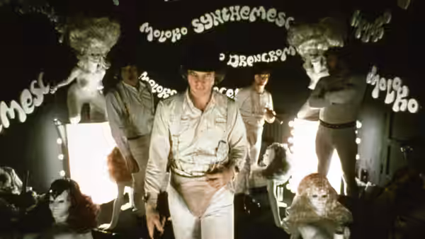 Alex (Malcolm McDowell) walking forward in the Korova Milk Bar among white sculptures