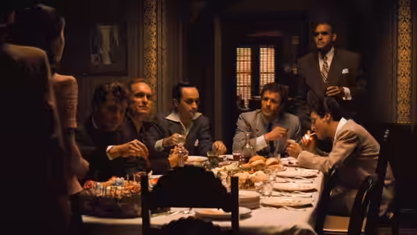 Several men seated at a long table covered with food and dishes