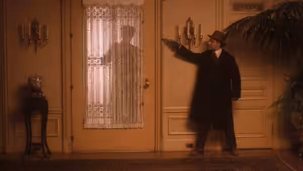Vito Corleone (Robert De Niro) aiming a pistol at a lace-curtained door