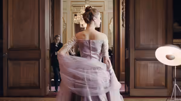 a woman in a pink gown standing in a doorway with a man behind her