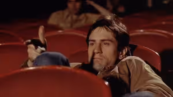 Travis Bickle (Robert De Niro) seated among empty red theater chairs