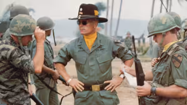Lieutenant Colonel Bill Kilgore (Robert Duvall) stands with hands on hips among troops