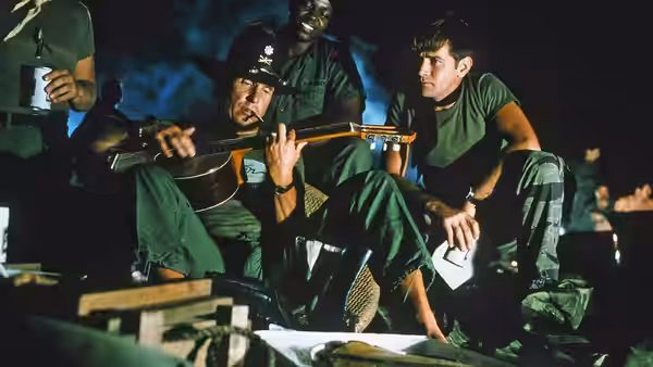 Lieutenant Colonel Bill Kilgore (Robert Duvall) plays guitar for soldiers at night
