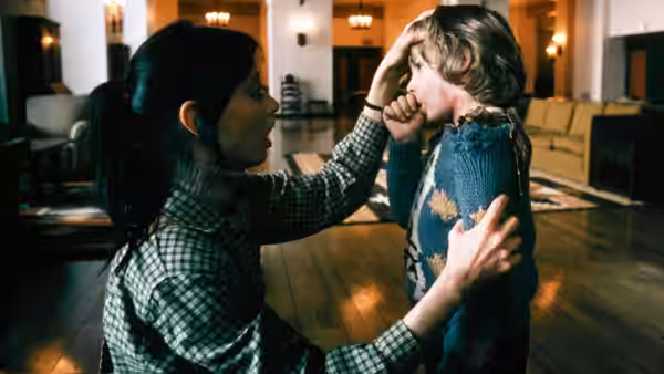 Wendy Torrance (Shelley Duvall) holds Danny (Danny Lloyd) by the shoulders in a hotel lobby