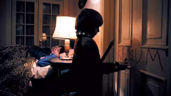 Danny (Danny Lloyd) stands before a door marked REDRUM while another boy lies in bed