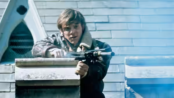 Mick Travis (Malcolm McDowell) aiming a rifle from a rooftop ledge