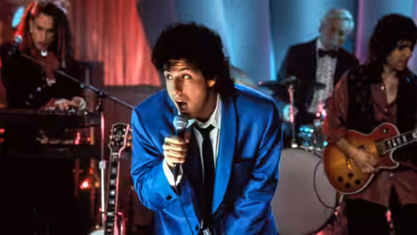 Robbie Hart (Adam Sandler) singing into a microphone wearing a blue suit
