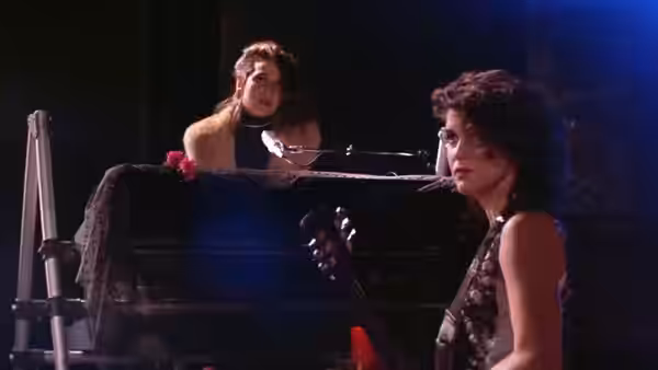 Wendy (Wendy Melvoin) plays piano while Lisa (Lisa Coleman) stands beside her