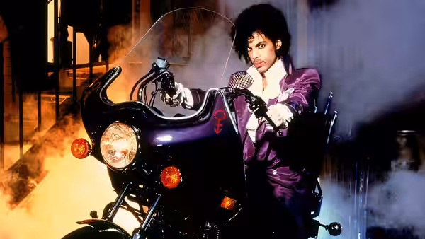 The Kid (Prince) sits astride his motorcycle amid smoke, gripping the handlebars