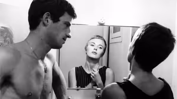 Michel (Jean-Paul Belmondo) stands beside Patricia (Jean Seberg) at a bathroom mirror